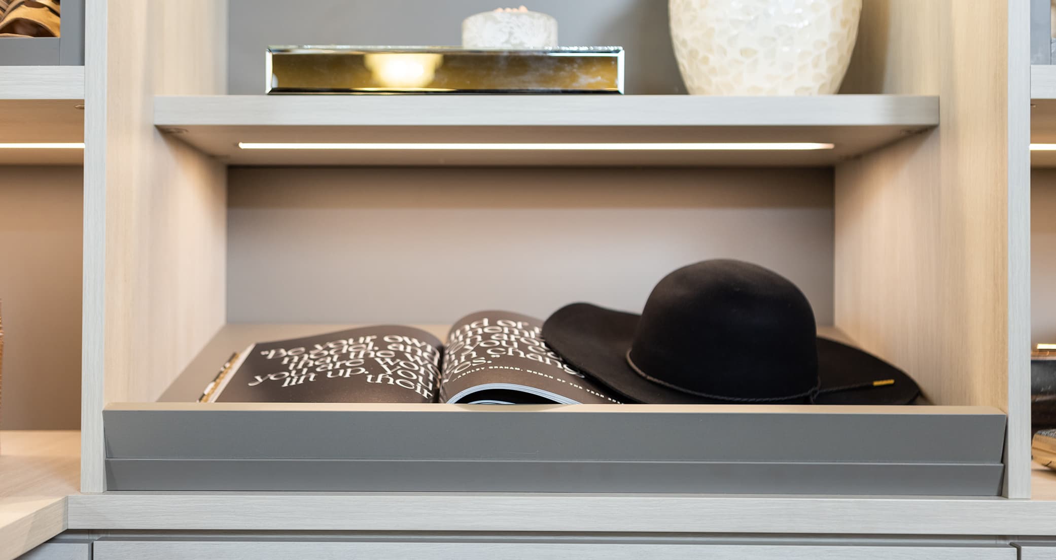 Open shelving in walk in closet with ribbon led lighting by California Closets