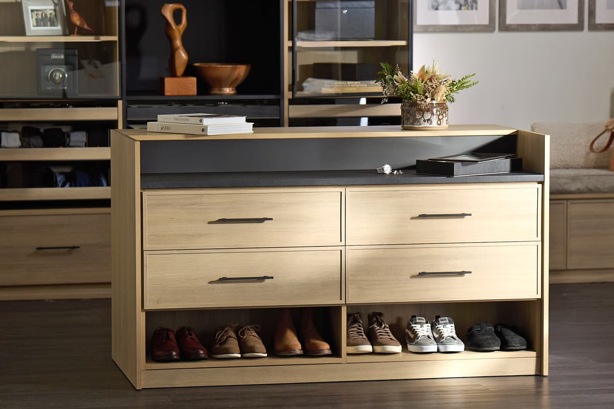 Storage center island in walk in closet for shoe storage and clothes accessories by California Closets